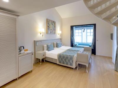 Helles Hotelzimmer mit Doppelbett, Sitzbereich, Holzfußboden und moderner Einrichtung.