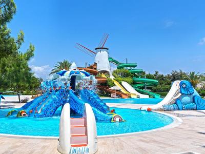 Bunter Wasserspielplatz mit Rutschen und Windmühle unter klarem blauem Himmel in einem Hotelpoolbereich.