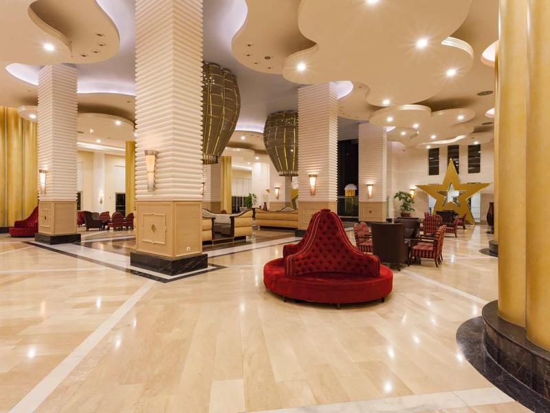 Luxe hotelreceptie met modern design, rode zitplekken en lichte marmeren vloer.