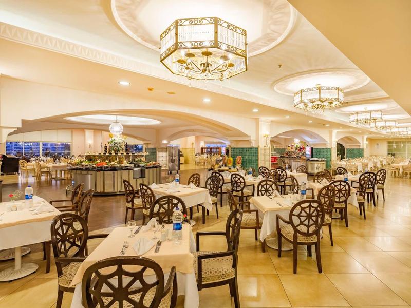 Elegant hotelrestaurant met decoratieve houten stoelen en warm licht.