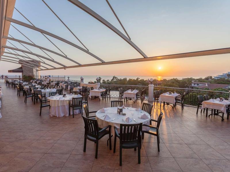 Open restaurantterras met gedekte tafels en uitzicht op zonsondergang