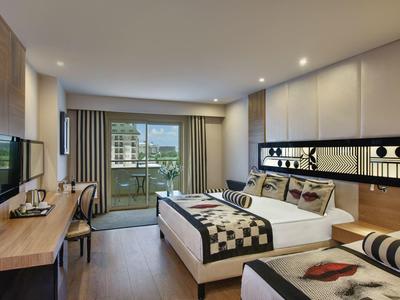 Modernes Hotelzimmer mit Doppelbett, großem Fenster, Schreibtisch und Balkon mit Aussicht.
