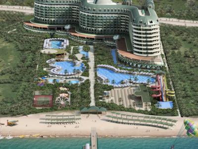 Großes Hotel mit geschwungener Fassade, Pools und Gartenanlagen am Sandstrand mit Meer davor.