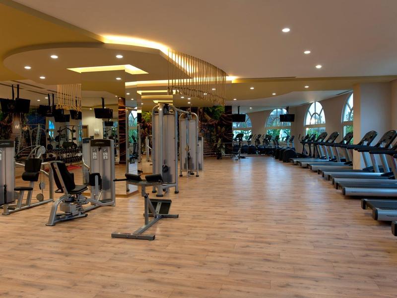 Prostorná posilovna s moderním vybavením a velkými okny v wellness centru.