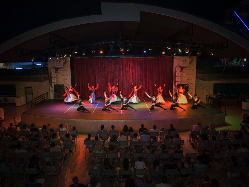 Taneční vystoupení na jevišti za účasti publika v tlumeně osvětleném prostoru