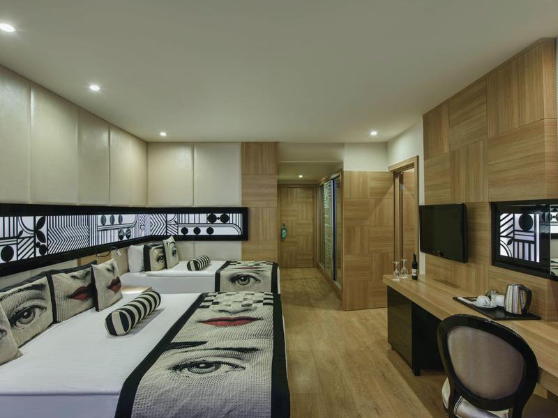 Moderní hotelový pokoj s uměleckou pohovkou, dřevěným nábytkem, televizí a měkkým osvětlením.