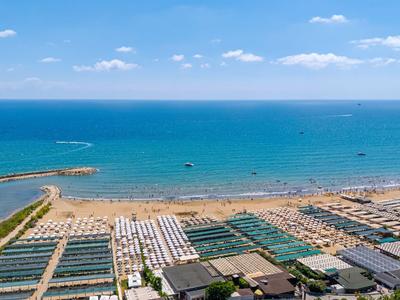 Uitgestrekt zandstrand met ligstoelen en blauwe zee onder heldere hemel
