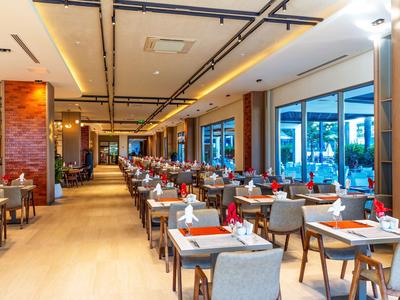 Modern restaurant met houten vloer, tafels met witte tafelkleden en grote ramen