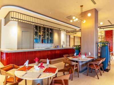 Lichte moderne restaurantinterieur met houten tafels en stoelen en een grote bar.