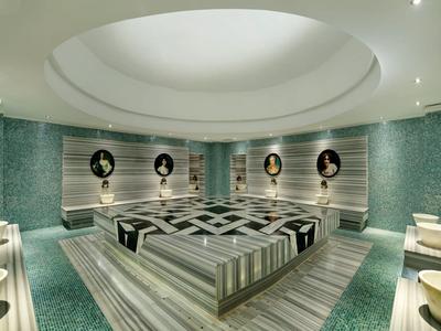 Grote ronde wellnessruimte met houten ligstoelen en ronde portretfoto's aan de muur.