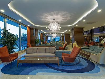 Moderner Lounge-Bereich mit grauer Couch, orangen Sesseln, rundem Teppich und großer Glasfront.
