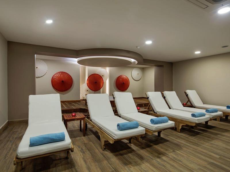 Ontspanningsruimte met witte ligstoelen en blauwe handdoeken onder zachte verlichting.