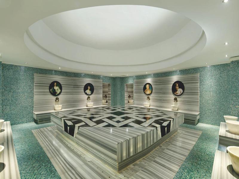 Luxe spa ruimte met verwarmde stenen ligstoelen, mozaïekmuren en stijlvolle wanddecoraties.