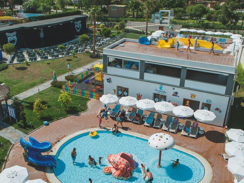 Hotel met twee zwembaden, parasols en uitzicht op de zee bij helder weer.