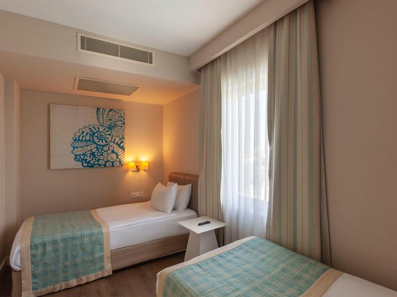 Gezellige hotelkamer met twee eenpersoonsbedden, zachte gordijnen en warme verlichting.