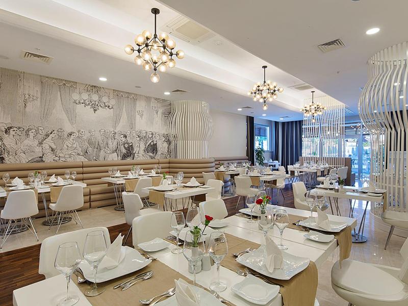 Modern ingericht hotelrestaurant met witte stoelen en elegante kroonluchters.