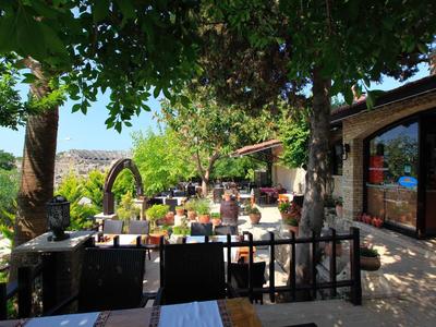 Slunná terasa s stromy, posezením a výhledem na údolí a hory.