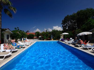 Großer, blauer Pool mit weißen Liegestühlen und Sonnenschirmen unter tiefblauem Himmel.