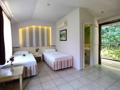 Una semplice camera d'hotel con due letti singoli, un comodino e un balcone con vista sul giardino.