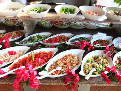 Různé saláty a přílohy v bílých misách zdobené růžovými květy.