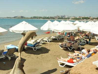 Spiaggia con ombrelloni e lettini, ospiti che godono una giornata di sole al mare.