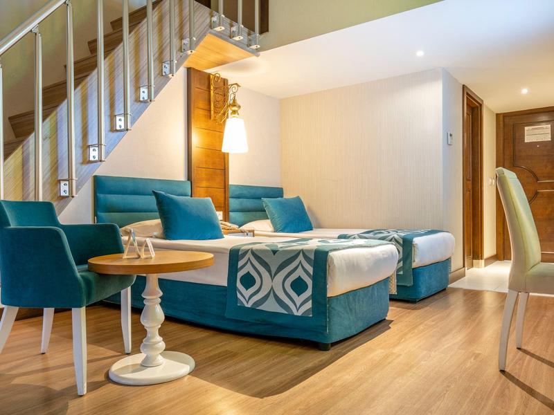 Salon moderne avec fauteuils bleus, canapé et sol en bois dans un appartement de vacances.