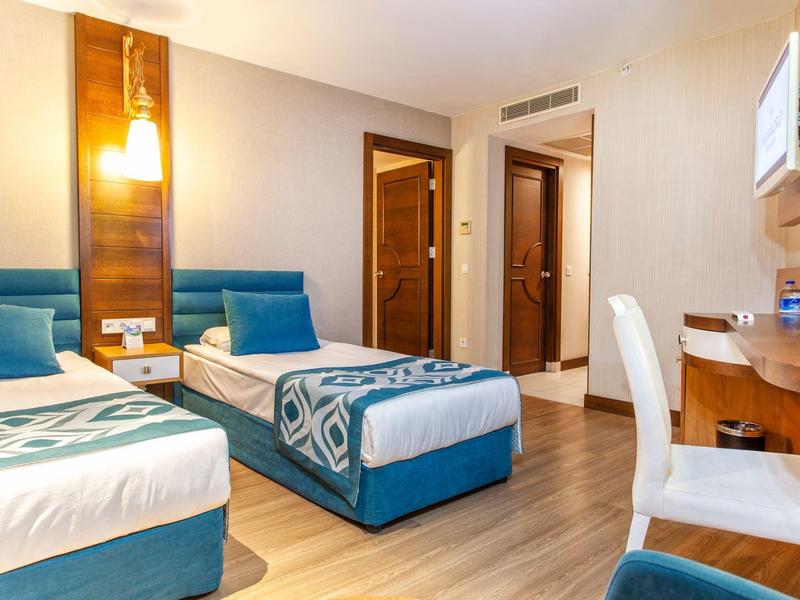 Chambre d'hôtel avec deux lits simples, bureau et intérieur moderne.