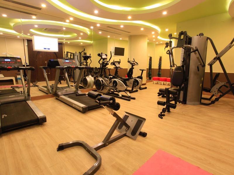 Salle de sport moderne avec tapis roulants, vélos et machines de musculation dans un hôtel.