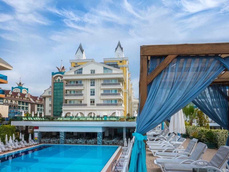 Grand piscine avec chaises longues et rideaux bleus par une journée ensoleillée à côté d'un hôtel.