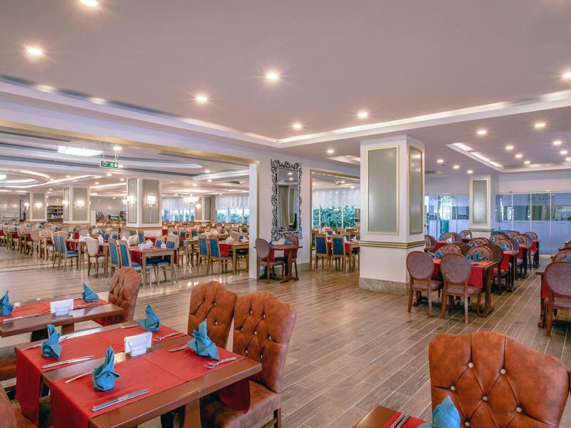 Espace de restaurant spacieux avec tables dressées et chaises confortables sous un éclairage doux.