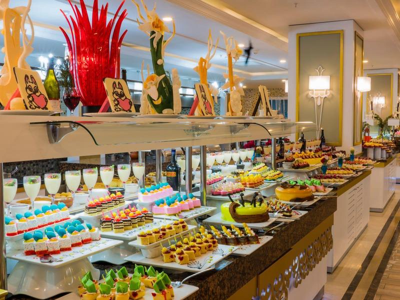 Buffet avec une variété de desserts colorés et des décorations artistiques dans un restaurant d'hôtel élégant.