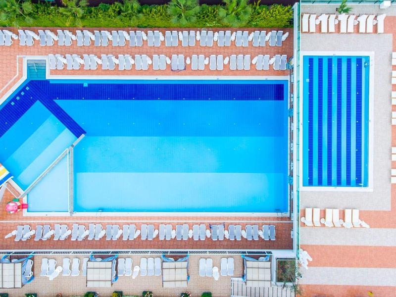 Vue aérienne d'une piscine d'hôtel avec toboggans aquatiques et jacuzzi adjacent.