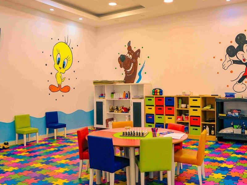 Salle de jeux colorée pour enfants avec peintures murales de dessins animés, mobilier vif et jouets dans un hôtel.