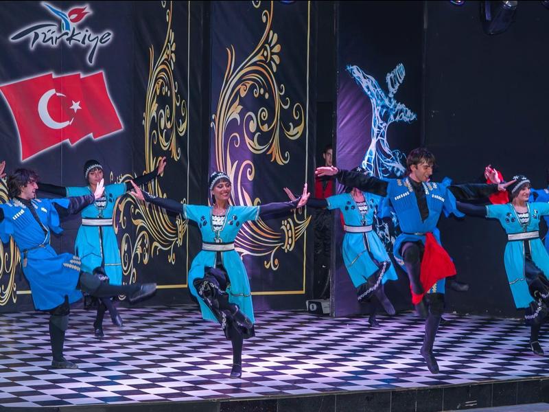Des danseurs en tenue turque traditionnelle exécutent un spectacle avec des décors ornés.