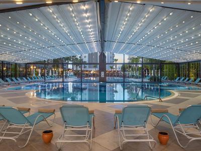 Piscina interna con sedie a sdraio blu e tetto in vetro luminoso.