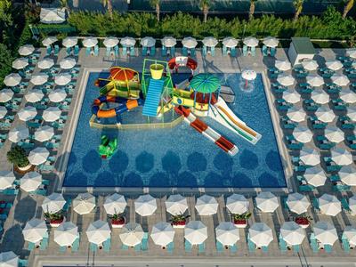 Piscina con area giochi acquatica circondata da ombrelloni e lettini.