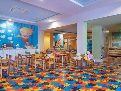 Sala giochi colorata con tavoli in legno e parete decorata con disegni marini animati.