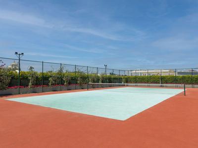 Campo da tennis vuoto con superficie rossa e cielo blu sullo sfondo