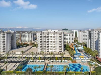 Vista panoramica di un complesso di appartamenti moderni con piscina sotto un cielo blu.
