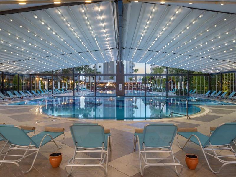 Piscina interna con sedie a sdraio blu e tetto in vetro luminoso.