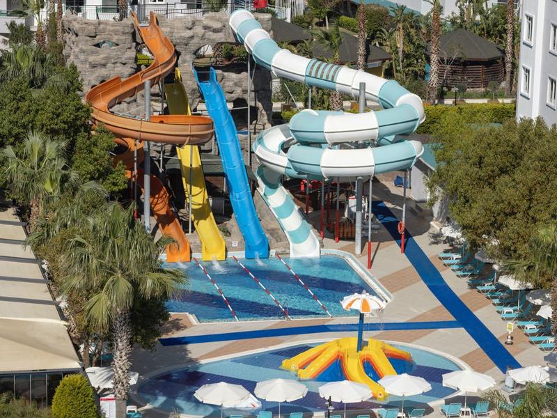 Parco acquatico con scivoli colorati vicino a una piscina e lettini.