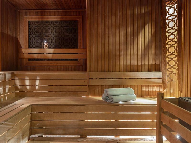 Sauna in legno con panchine, luce soffusa e asciugamani piegati.