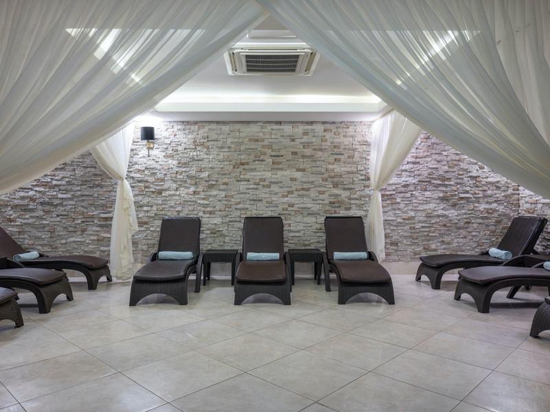 Zona relax spa con lettini sotto tende bianche in ambiente moderno.