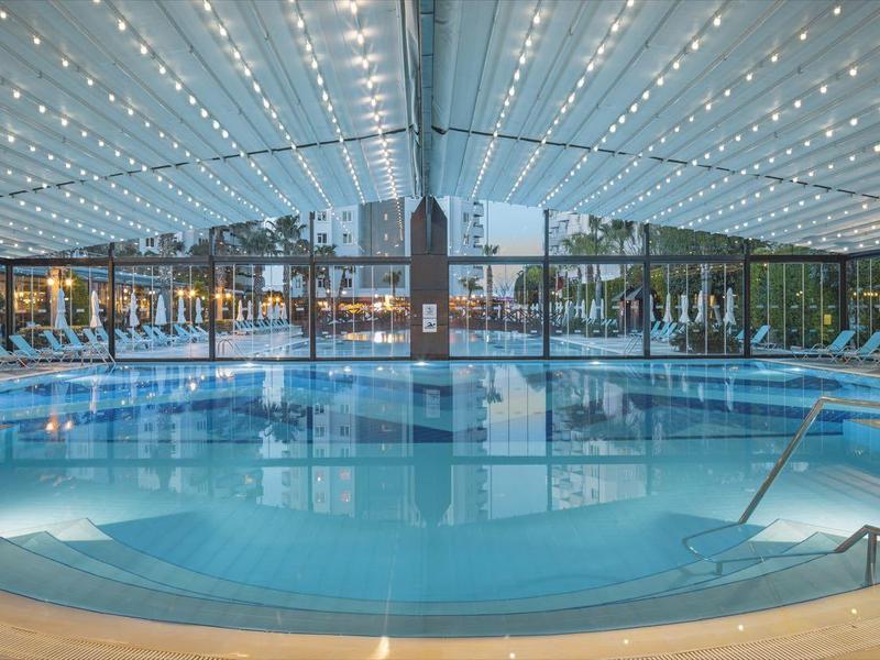 Piscina interna rotonda in un hotel moderno con tetto trasparente e lettini.