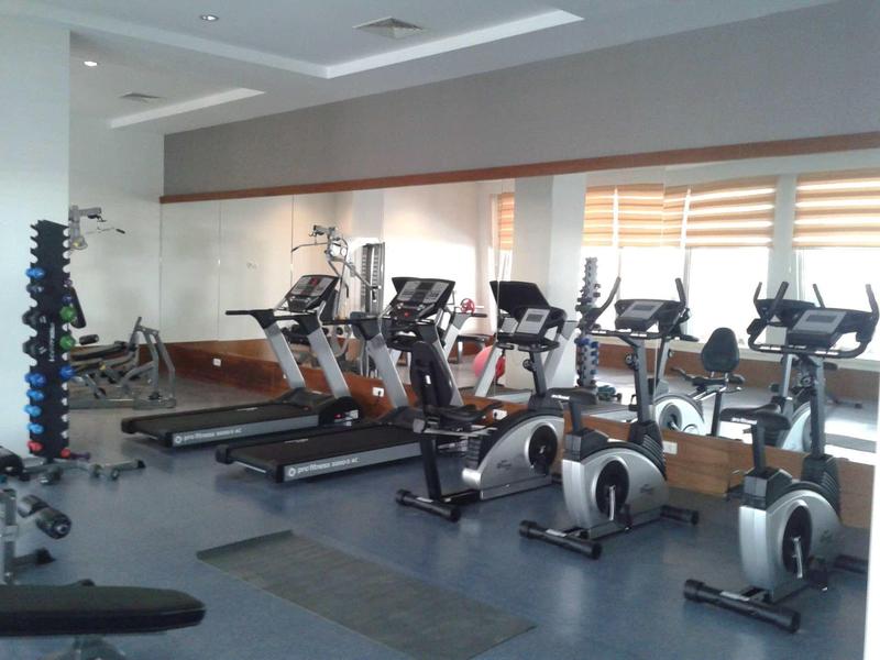 Modern exercise equipment and treadmills in a bright gym with mirrored wall.