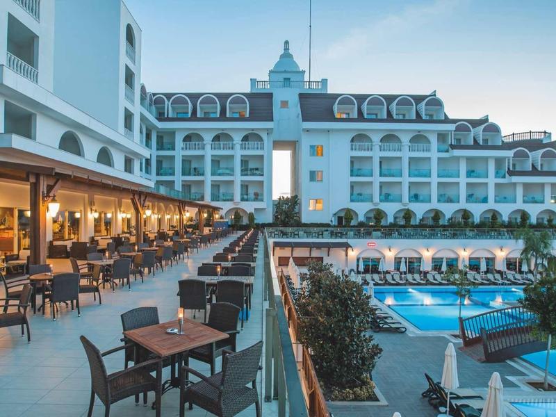 Luxury hotel with outdoor pool, terrace, and numerous seating areas in clear weather.