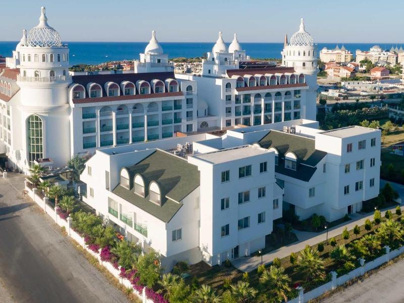 Large white hotel building with towers on the coast overlooking the sea.