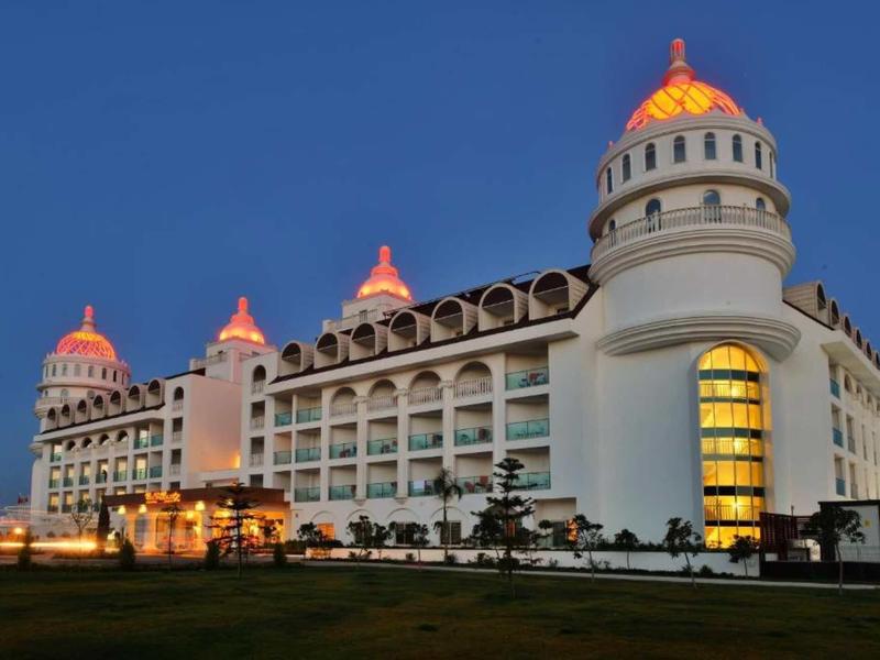 Large illuminated hotel building with towers at night against clear sky.