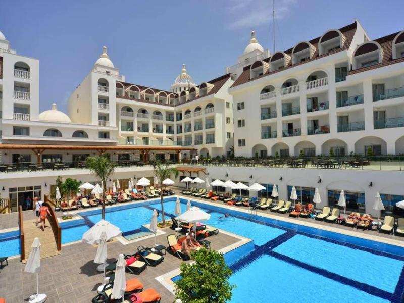 Large multi-story hotel with an outdoor blue swimming pool and lounge chairs.