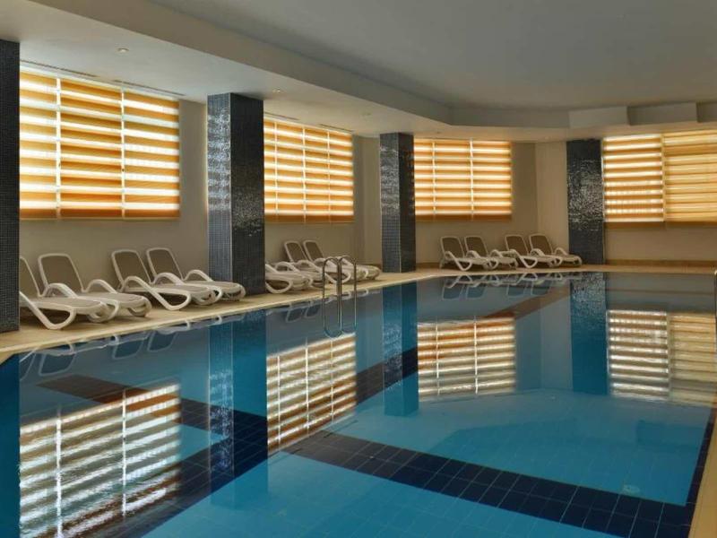 Indoor pool with blue water and white lounge chairs along the wall.